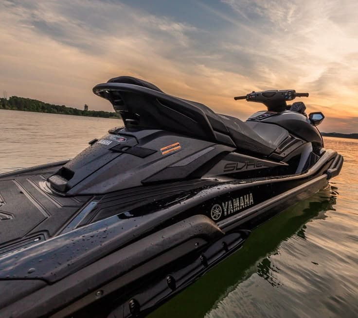 Sleek black Yamaha WaveRunner floating on calm water under a vibrant golden sunset sky.